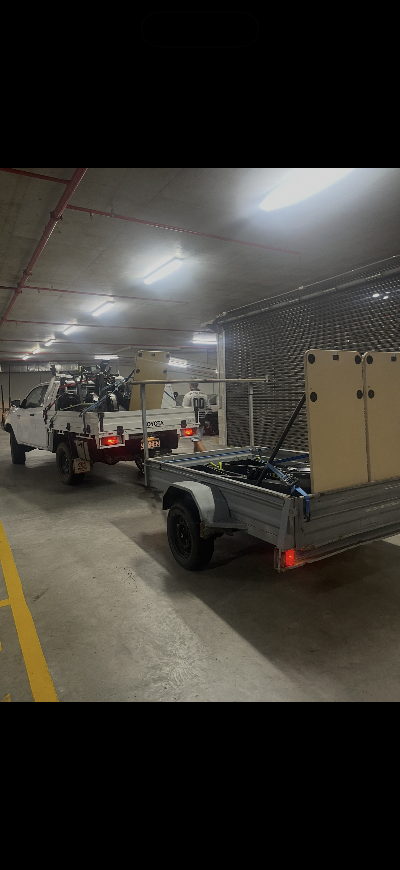 A ute and trailer loaded with gym equipment in a basement car park, ready to deliver to the first gym