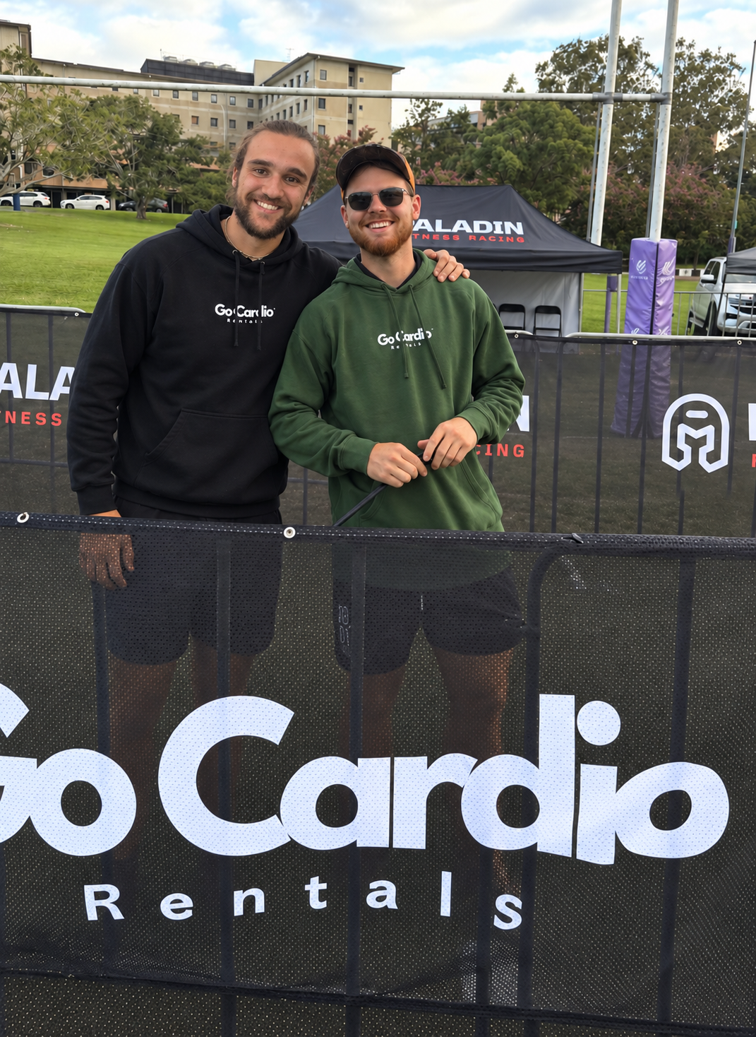 Jake and Kade behind a Go Cardio Rentals banner at a Paladin Fitness Racing event